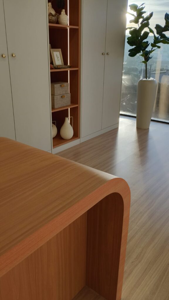 Closet planejado com bancada curva de madeira e nichos iluminados