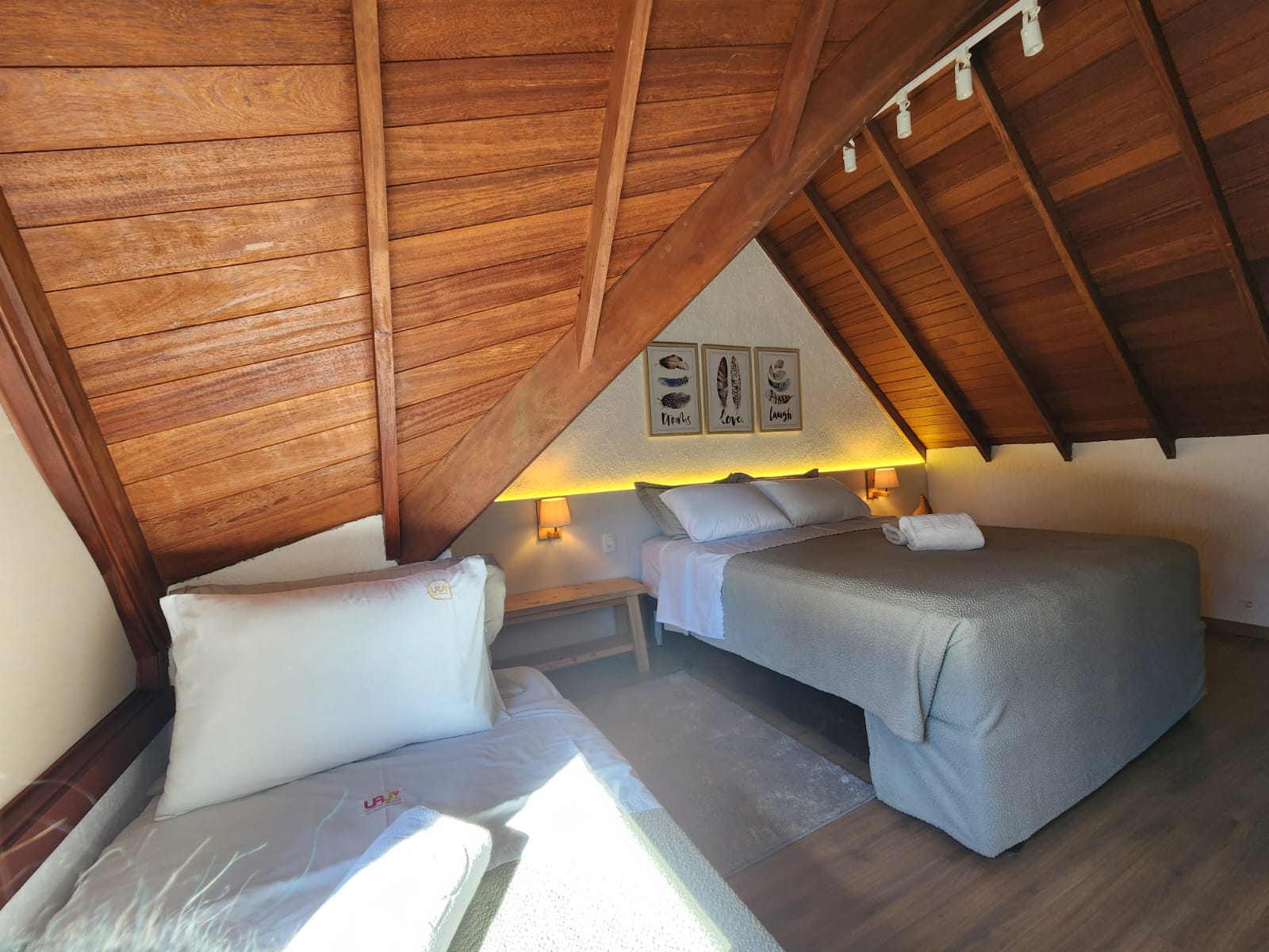 Quarto de sótão de pousada com marcenaria sob medida e telhado de madeira aparente