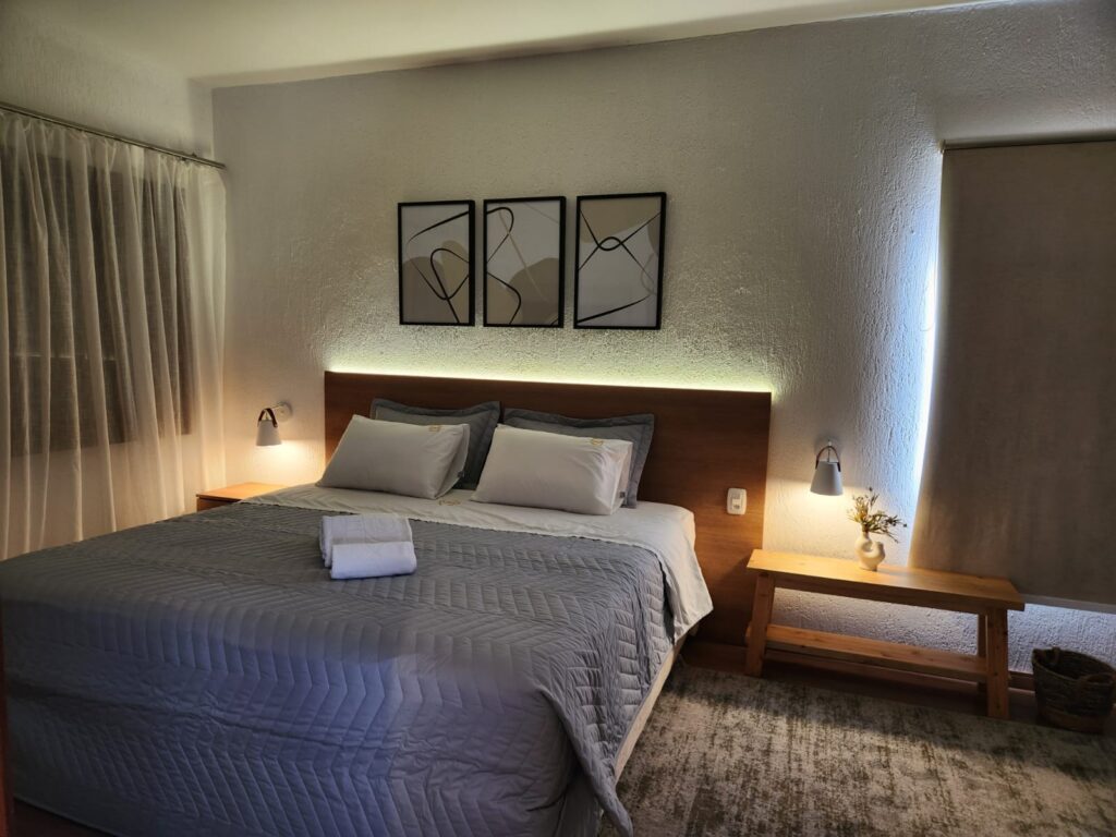 Quarto de pousada com cabeceira planejada e iluminação indireta